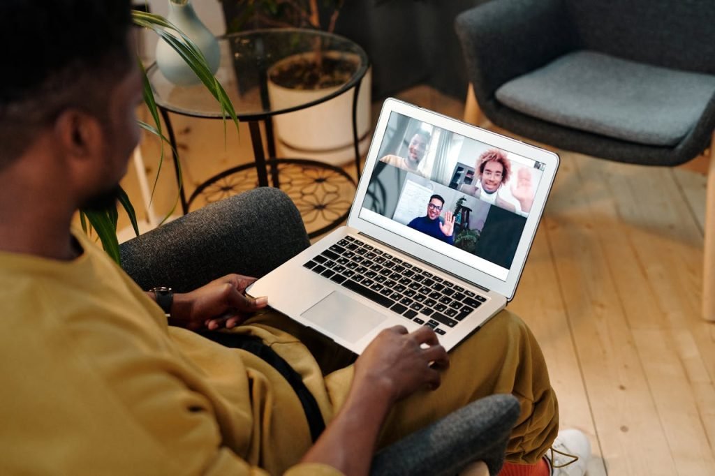 Person sitting in a chair using laptop for a virtual meeting in a cozy home office setting.