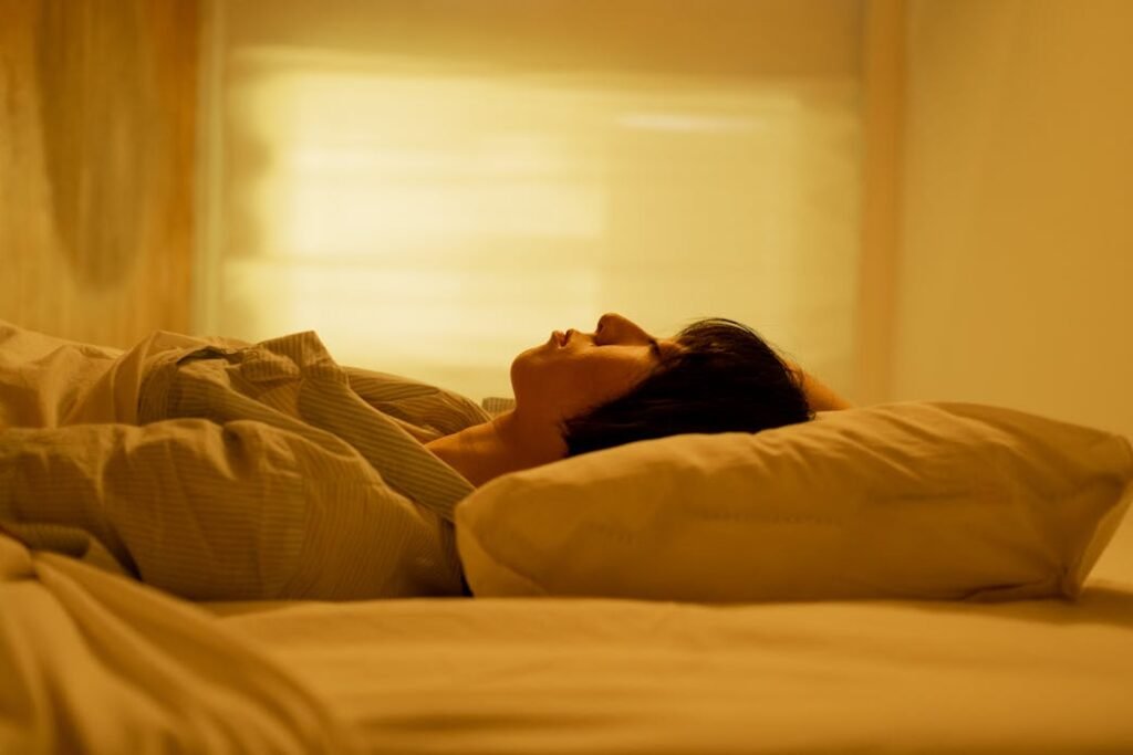 A person peacefully resting indoors against a soft pillow under warm lighting.