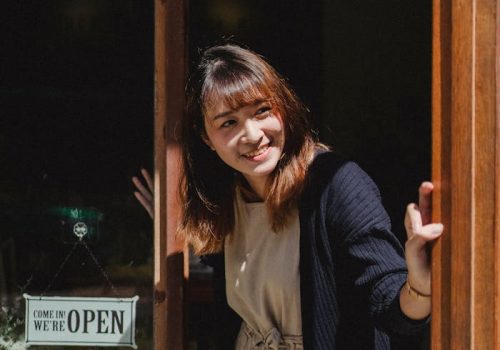 smiling-asian-woman-in-apron-opening-store-door-5409662 Positive smiling Asian female store worker opening store door and looking away contentedly