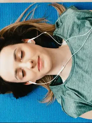 tranquil-woman-resting-on-yoga-mat-in-earphones-at-home-4498187(1) copie Hypnose Régressive